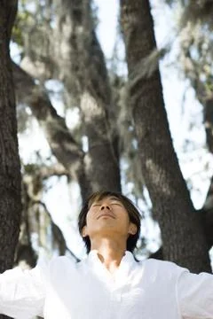 Man standing amongst trees, head back and eyes closed Stock Photos