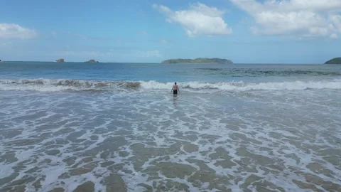 Man Standing and Catching a Wave on a Beach Stock Footage 303281694