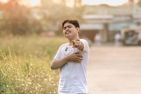 A man standing and smiling. the man points at the camera in the sunny after.. Stock Photos