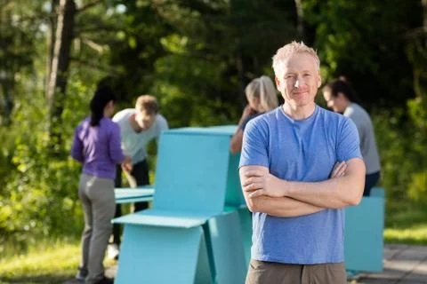 Man Standing Arms Crossed While Friends Making Planks Pyramid 写真素材