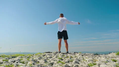 Man standing with arms raised, reaching the top. A man salutes the sun. Stockbeeldmateriaal 201245039