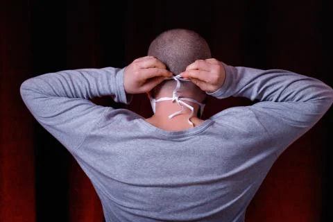 A man standing back to camera tying a medical gauze mask Stock Photos