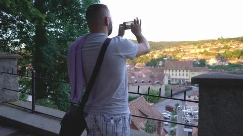 Man standing on the balcony and doing photos of the old town  Stock Footage 103505959