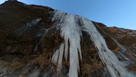 Man standing at the base of a frozen waterfall in Iceland Stock Footage 302646416