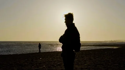 Man standing on the beach, beautiful seaside, sunset. Slow motion. Stock Footage 80307311