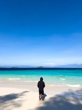 Man Standing on Beach Looking at Ocean Fotos Stock