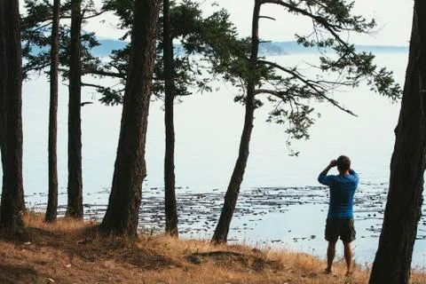 Man standing on a beach, looking through binoculars, San Juan Islands in the Stock Photos
