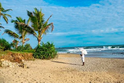 Man standing on beach under sun parasol Stock Photos