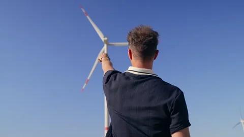 Man Standing From Behind Looking at Wind Turbine and Blue Sky Stock Footage 340105552