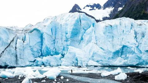 Man standing below massive glacier calving face Stock Photos