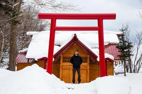 Man standing below red gate to Japanese building, ancient architecture style Stock Photos