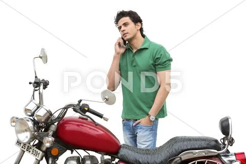 Man standing beside a motorcycle and talking on a mobile phone Stock Photos