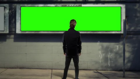 Man Standing Before Blank Green Screen Billboard Mockup, Urban Scene Stock Footage 342120824