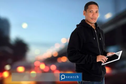 Man standing with blur city background using computer tablet with search en.. Stock Photos