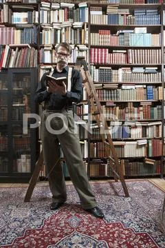 A man standing in a bookstore reading a book Stock Photos