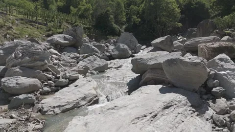 Man standing on boulders in a river as the drone flies backwards Stock Footage 288728408