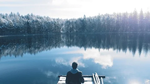 Man standing on the bridge in beautiful winter lake surrounded by forest Stock Footage 105420860