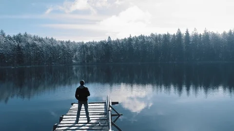 Man standing on the bridge in beautiful winter lake surrounded by forest Stock-Footage 105420910