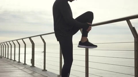 Man standing on the bridge doing exercises for legs before jogging Stock Footage 132042166