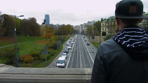 Man standing on bridge looking down at passing cars, intending to commit suicide Stock Footage 75918831