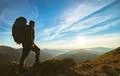 The man standing with a camping backpack on the rock with a picturesque sunse Photo