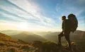 The man standing with a camping backpack on the rock with a picturesque sunri Photo