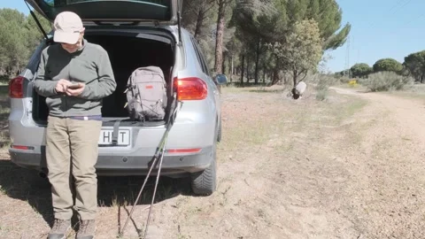 Man Standing by Car Trunk in a Forest Checking Smartphone Stock Footage 309099081