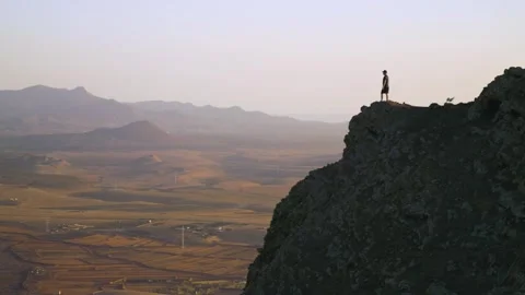 Man standing on cliff edge overlooking vast volcanic landscape cinematic 스톡 동영상 331194095