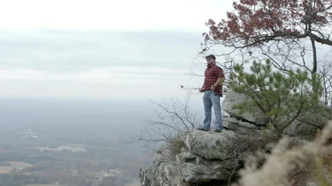 Man Standing on Cliff Edge Overlooking Mountain Valley Stock-Footage 343934333