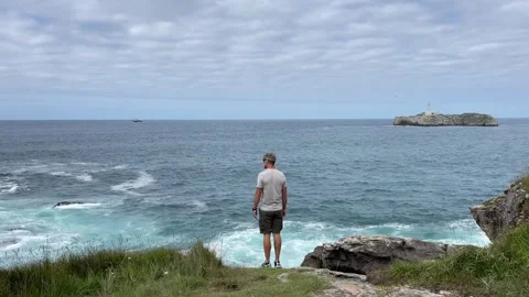 Man standing on the cliff overlooking the ocean 스톡 동영상 249381836