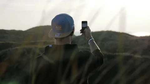 Man standing on coast and taking pictures on mobile phone Stock Footage 71564825