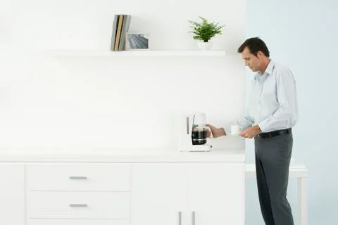 Man standing by counter, getting coffee, side view Foto stock