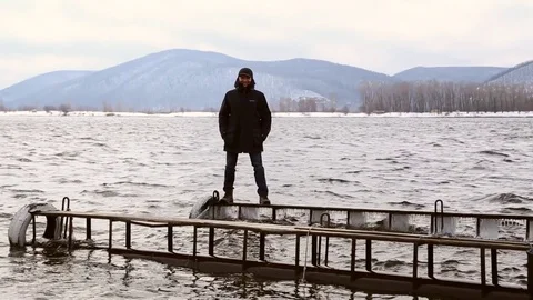 Man standing dangerously on a narrow icy pier Stock Footage 74159938