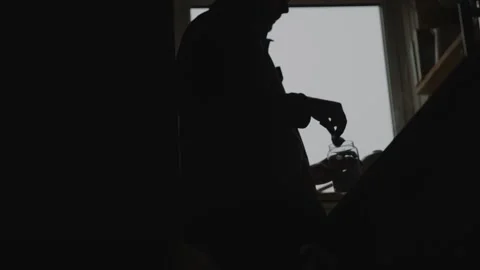 A man is standing in a dark room with a window Stock Footage 301618469