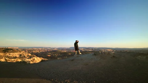 Man Standing on Desert Cliff Edge Overlooking Vast Canyon Landscape at Sunset. Vidéo 342490318