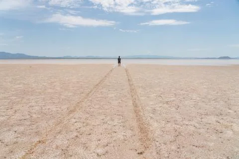 A man standing in the desert at the edge of standing water from recent rain. Stock Photos