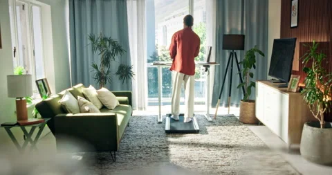 Man, standing desk and treadmill in lounge with remote work from home for Stock Footage 330235697
