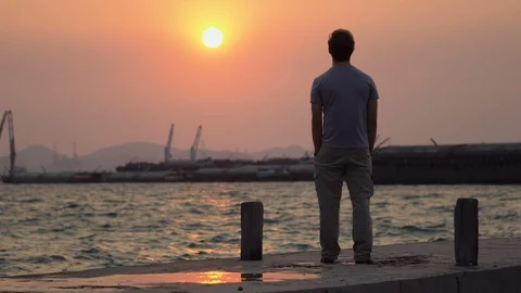 Man Standing on Dock Looking at Beautiful Sunset Over Ocean Stock Footage 126259168