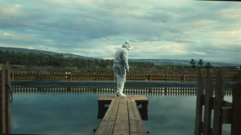 Man standing up on a dock over water while wearing full biological protecti.. Stock Footage 275255950