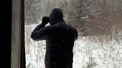 Man Standing in Doorframe of Old Mountain House Looking at Winter Forest Video stock 334239366