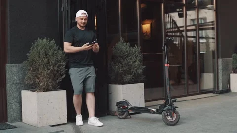 Man standing with e-scooter in city downtown and taking selfie with smartphone Stock Footage 229257574