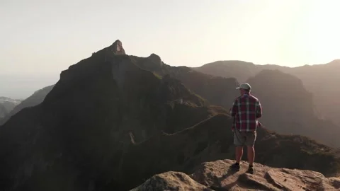 Man standing on the edge of a cliff in the mountains of Madeira island, Portugal Stock Footage