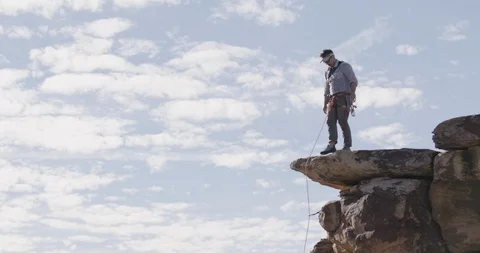 Man standing at the edge of a cliff pulling the rope Stock Footage 145281236