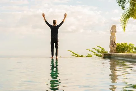 A man standing at the edge of infinity pool Stock Photos