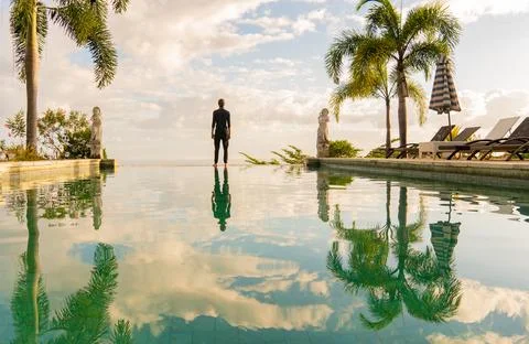 A man standing at the edge of infinity pool Stock Photos