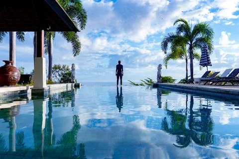 A man standing at the edge of infinity pool Stock Photos