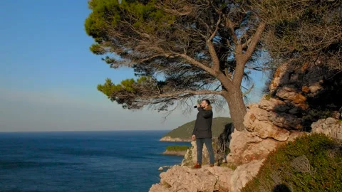 A man standing on the edge of a mountain and looking out to the sea. Montenegro. Stock Footage 273566487