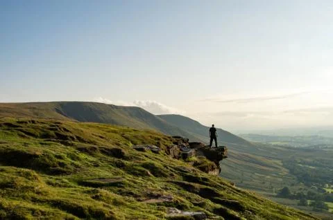 A man standing on the edge of a mountain, looking out across an escarpment Stock Photos