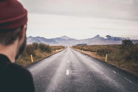 Man standing on empty road in front of a mountain range with fog. Lovely la.. Stock Photos