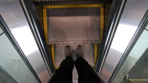 A man standing on an escalator, looking down at his feet while ascending. Stock Footage 318267015